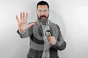 Bearded detective with serious face showing police badge and making stop sign with hand.