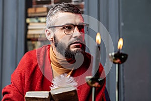 Bearded diviner feeling thoughtful after reading ancient magician book