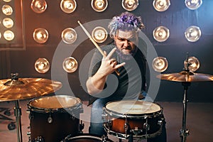 Bearded drummer with colorful hair, rock performer