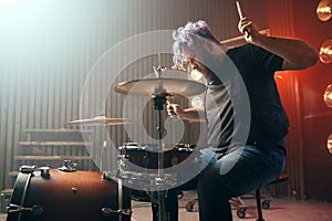 Bearded drummer with colorful hair on the stage