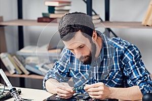 Bearded engineer examing micro circuit
