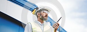 Bearded engineer on produce site. Wide image
