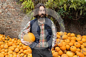 Bearded farmer with pumpkin on a background of a pile of pumpkins