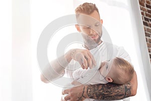 Bearded father feeding baby boy while
