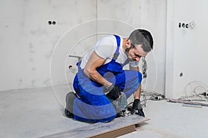 Bearded foreman sawing a wooden board with a jigsaw