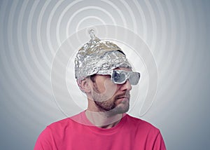 Bearded funny man in a cap of aluminum foil sends signals