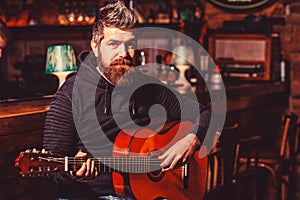 Bearded guitarist plays. Bearded man playing guitar, holding an acoustic guitar in his hands. Play the guitar. Music