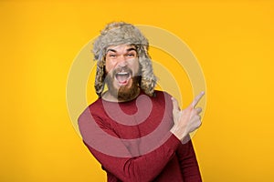Bearded guy in funny winter hat, screaming and pointing away up