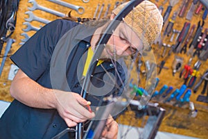 Bearded guy repairing bicycle in the workshop