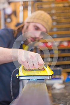 Bearded guy waxing ski in the workshop