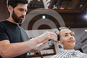 bearded hairdresser trimming hair of positive