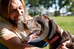 Bearded hairy man caressing adorable Kurzhaar dog