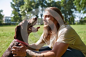 Bearded hairy man caressing Kurzhaar dog in park