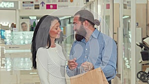 Bearded handsome man and his lovely wife looking inside shopping bags