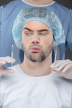 bearded handsome man in medical cap choosing beauty injections