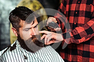 Bearded handsome man visiting hairstylist. Barber shop. Bearded hipster getting hairstyle. Male hairstylist serving client