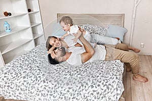 Handsome man raising his baby over his head while his wife looking at them