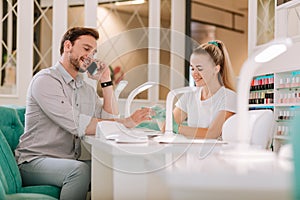 Bearded handsome metrosexual getting manicure in nail bar photo