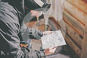 Bearded handsome snowboarded taking rest after ride session.Young man looks at the mountain map on sunny terrace