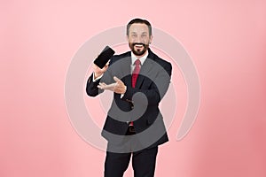 Handsome sales man in suit and red tie showing his phone to the camera and pointing to it. Make business online happy