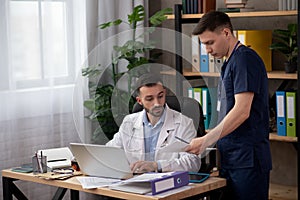 Bearded head doctor reviewing the report of young intern