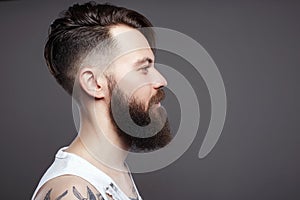 Bearded hipster. Boy with stylish haircut and tattoo