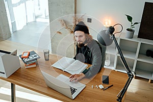 Bearded hipster doing home work while studying at university