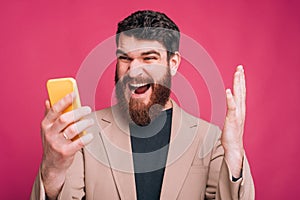 Bearded hipster man is shouting at his phone.