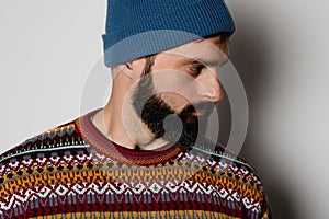 Bearded hipster wearing blue beanie and colored jumper