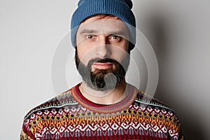 Bearded hipster wearing blue beanie and colored sweater