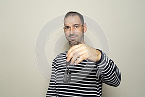 Bearded Hispanic man in his 40s wearing striped sweater, hold car key, keyless system, look at camera isolated on plain