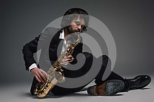 bearded jazzman playing saxophone while sitting