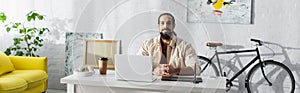 bearded latin freelancer sitting near laptop photo