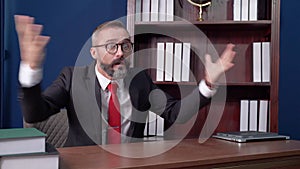 Bearded leader wearing glasses and a suit sitting in the office. He is very angry with his followers. And fired from the room due