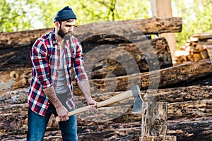 bearded lumberjack in checkered shirt chopping log photo