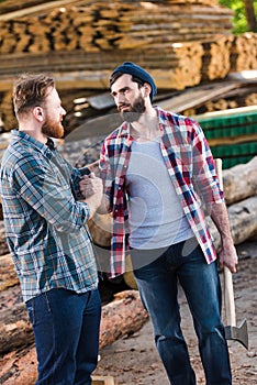 bearded lumberjack in checkered shirt holding axe and shaking hands with partner