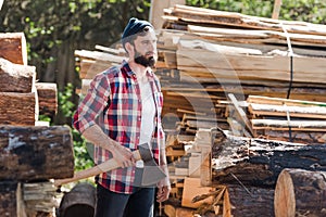 bearded lumberjack in checkered shirt standing with axe photo