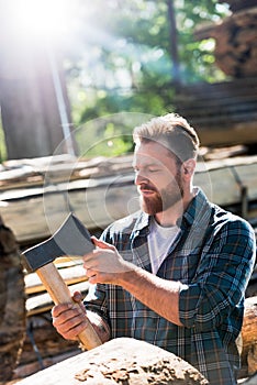 bearded lumberjack in checkered shirt touching blade of axe photo