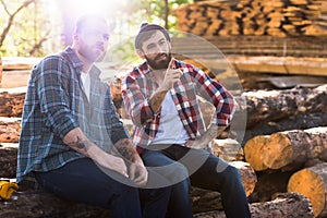 bearded lumberjack pointing by finger to sitting colleague