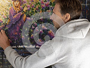 Bearded male artist and his painting on canvas