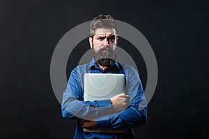 Bearded male businessman holding a computer in his hands isolated on black background. Businessman using his laptop, pc