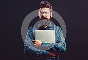 Bearded male businessman holding a computer in his hands isolated on black background. Businessman using his laptop, pc