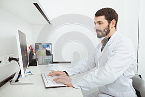 Bearded male dentist working at his office