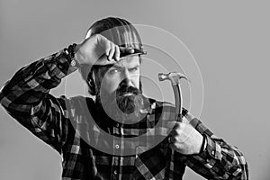 bearded male hipster in checkered shirt and laborer helmet, working