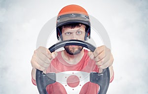 Bearded male in red helmet with steering wheel. car driver concept