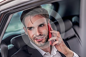 Bearded male sitting at backseat of car, talking on phone