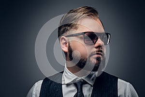 Bearded male in sunglasses wearing waistcoat and bow tie.