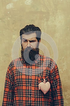 Bearded man with beard with rosy textile heart on shirt