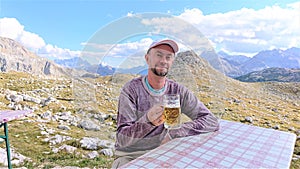 Bearded man with a beer and Italian Alps.