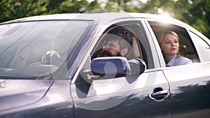 Bearded man and blonde lady sit in blue car. Husband and wife drive in a car and they are transported to summer trip
